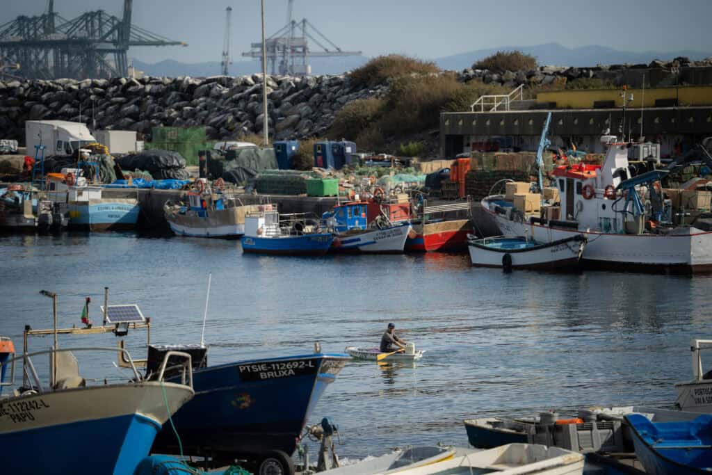 Harbor with colorful boats docked and industrial cranes in the background, showcasing maritime activ.