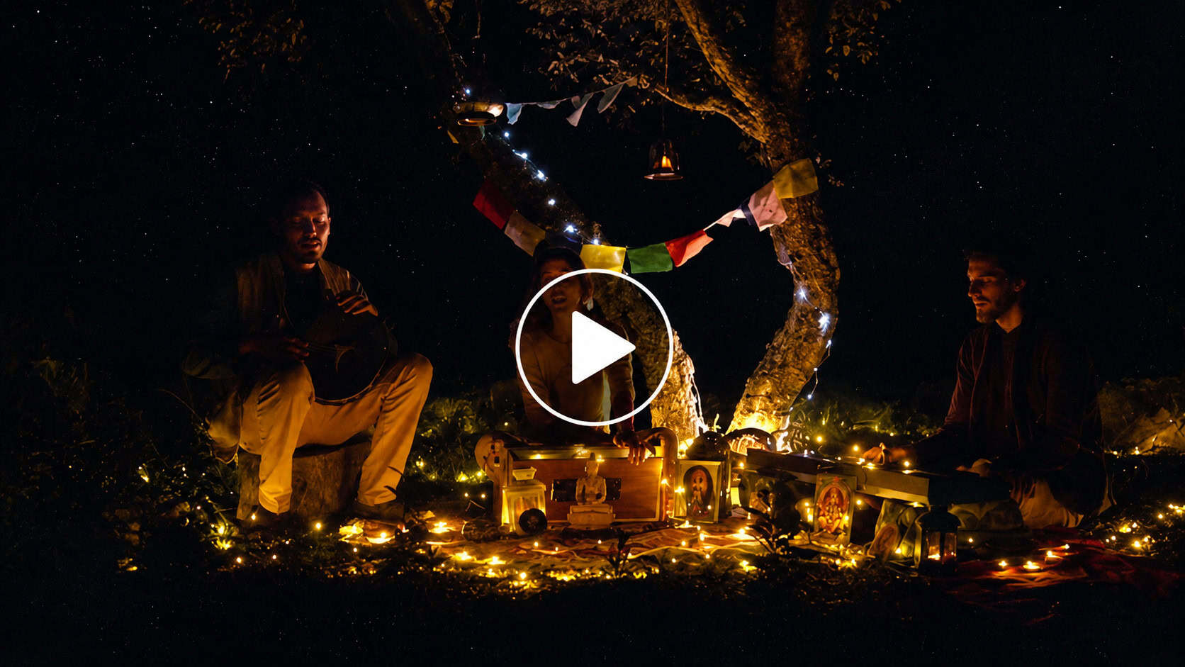 Nighttime outdoor performance with illuminated decorations and performers under a tree.