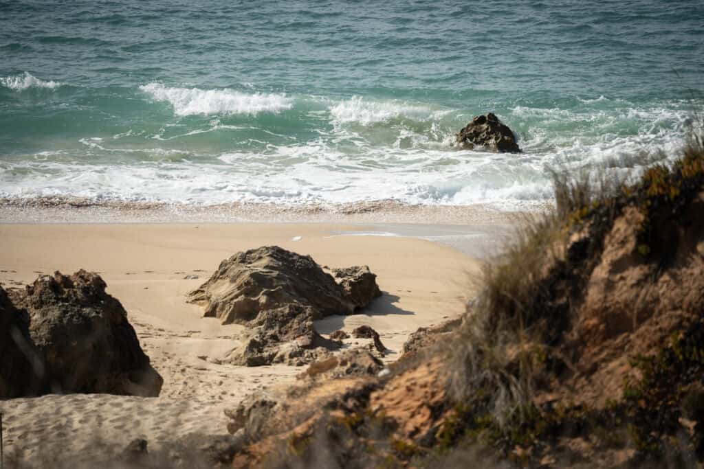 Beautiful rocky shoreline with gentle waves crashing onto sandy beach.